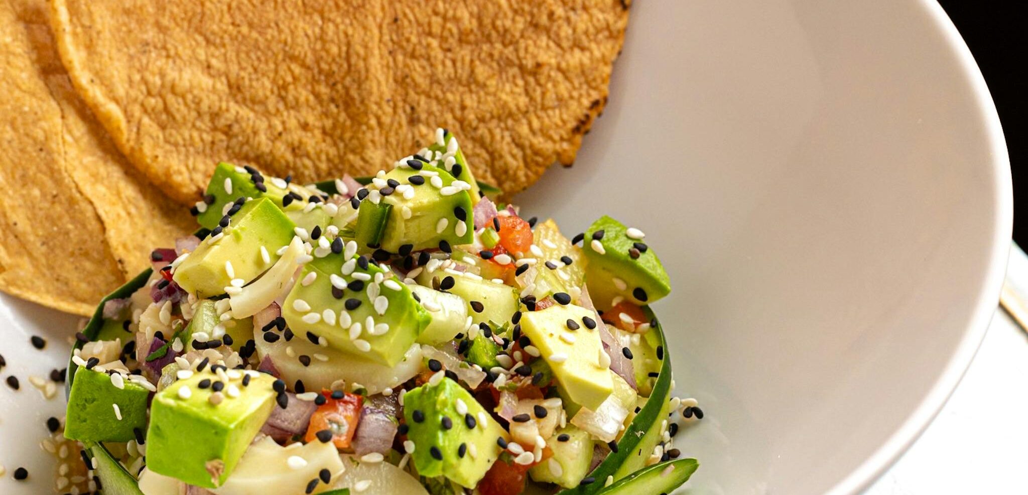 A vibrant aguachile dish featuring fresh avocado and sesame seeds, perfect for a summer meal.